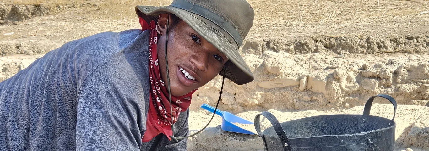 Davis with a pick axe at an excavation site