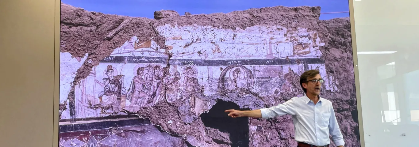 Aravecchia pointing to a picture of a desert landscape