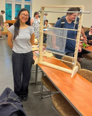 student standing beside a homemade loom