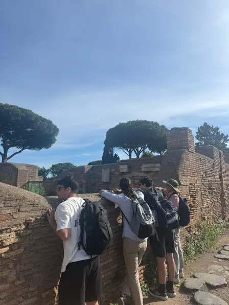 Professors Erdman and Moore peer into an excavated building with students