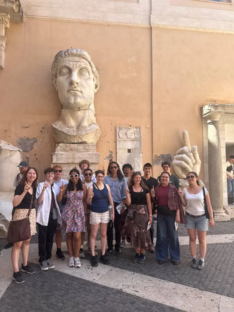 group picture in front of giant Cesar head and hand statue