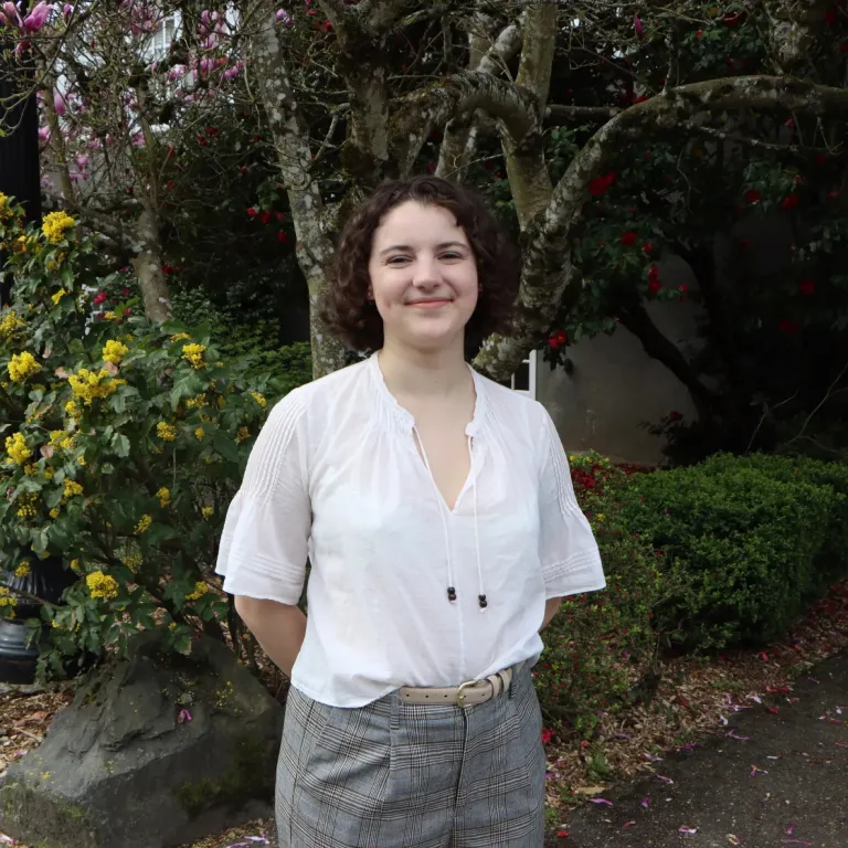 A woman in professional clothing standing before a forest