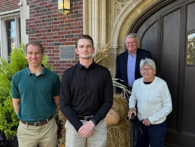 Four people standing in front of an old-fashioned wood doorway