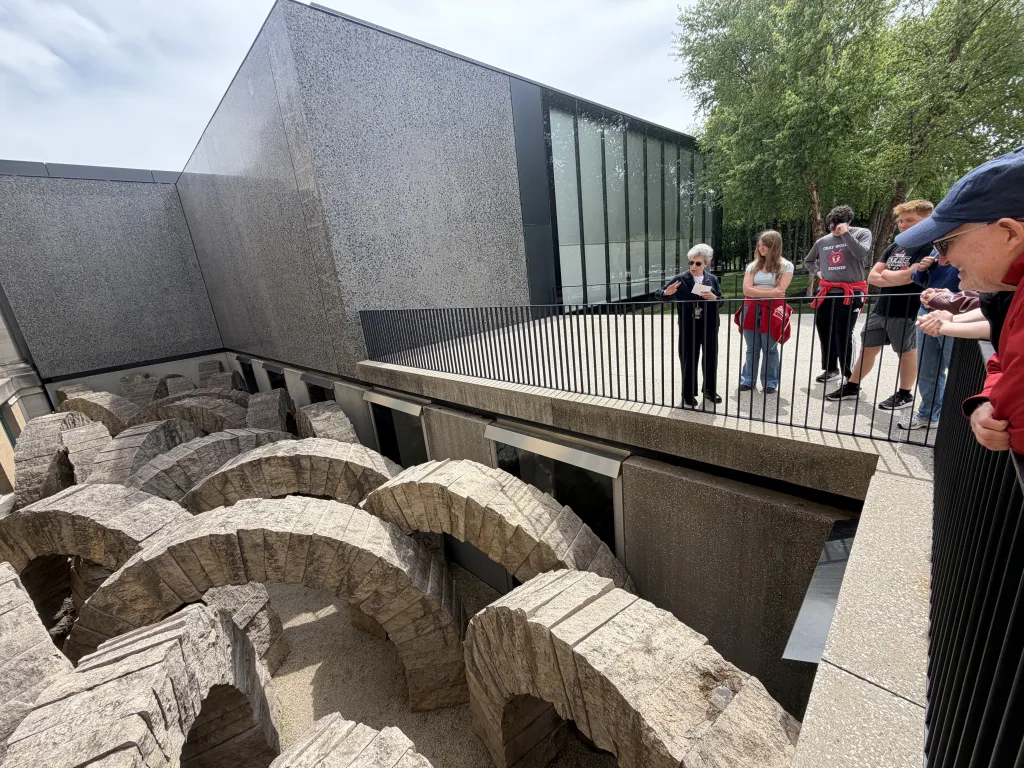 students and Prof. Moore look down into an installment of arches