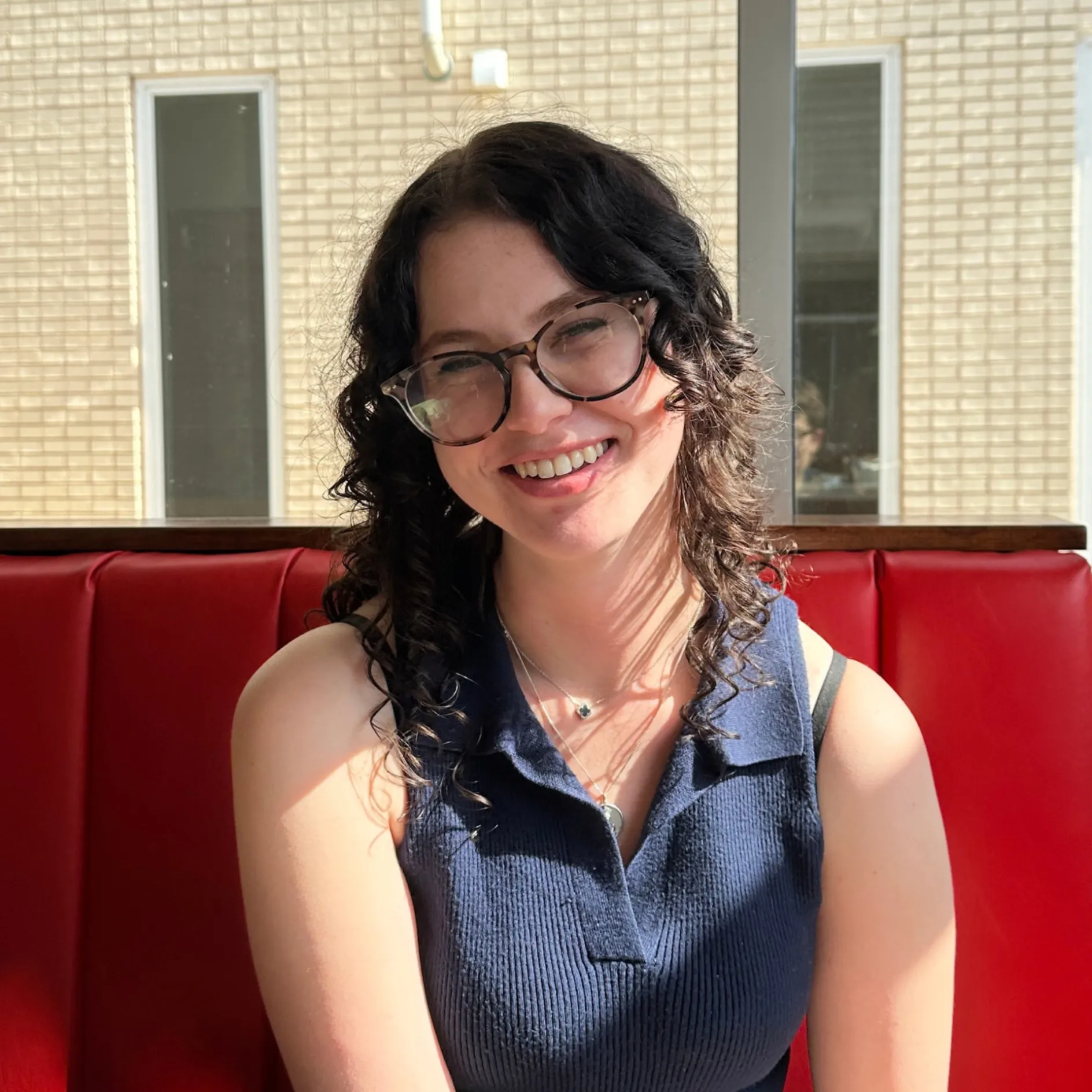 "Image of a woman smiling while sitting in a booth"