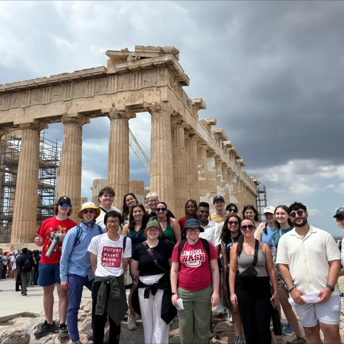 a group of students standing in front of the Greek ruins