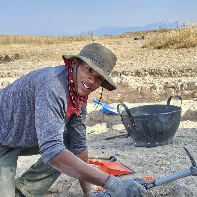 Davis with a pick axe at an excavation site