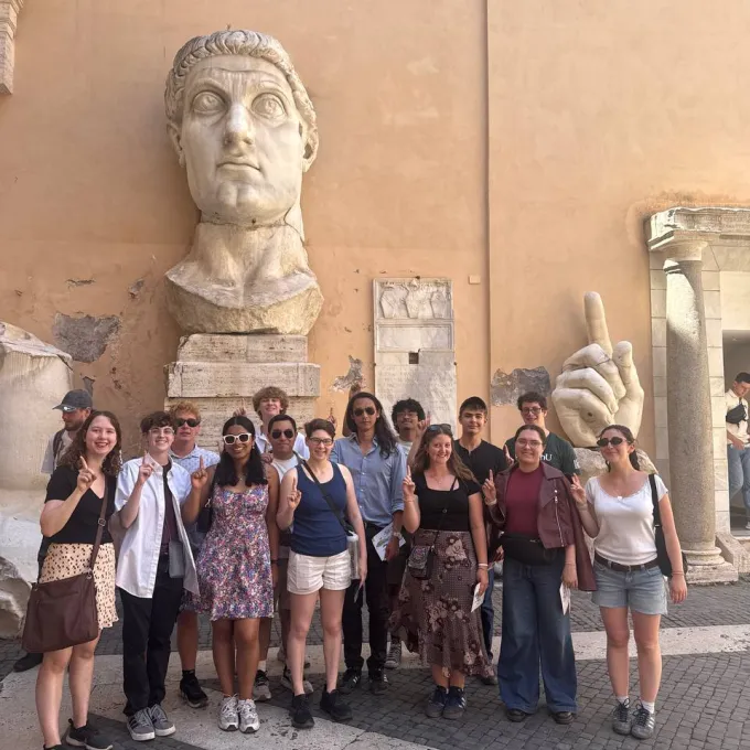 group picture in front of giant Cesar head and hand statue